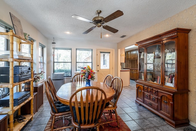 dining room with dark tile patterned flooring, ceiling fan, and a textured ceiling