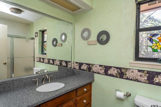 bathroom with vanity, a shower with shower door, a textured ceiling, and toilet