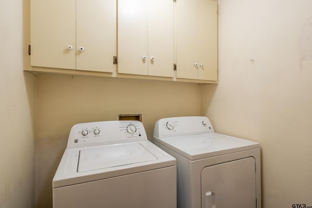 washroom with washer and dryer and cabinets