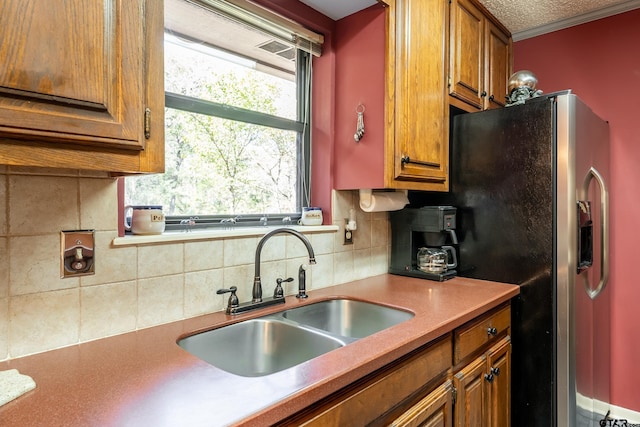 kitchen with backsplash, stainless steel fridge with ice dispenser, sink, and a textured ceiling