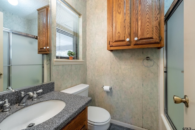 full bathroom featuring vanity, a textured ceiling, toilet, and enclosed tub / shower combo