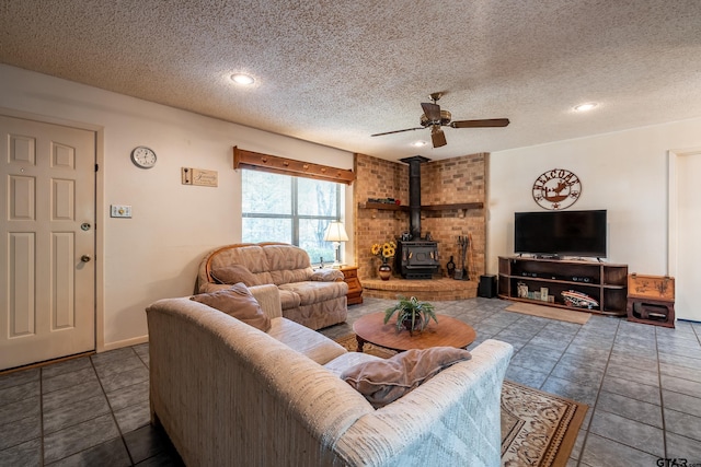 tiled living room with a textured ceiling, a wood stove, and ceiling fan