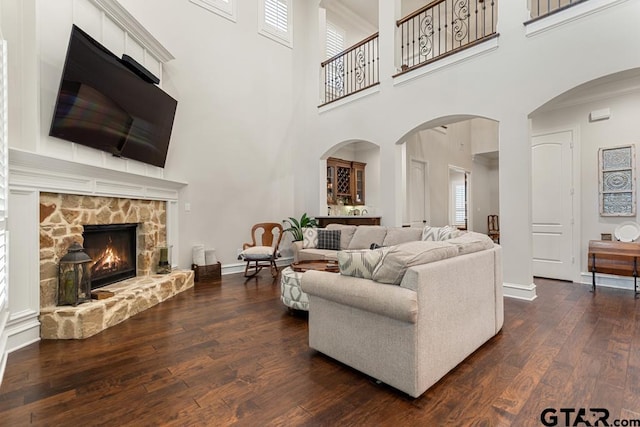 living room featuring a fireplace, dark hardwood / wood-style floors, and a towering ceiling