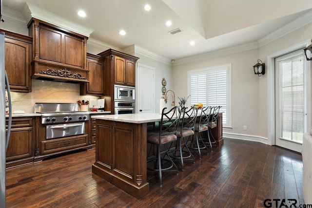 kitchen featuring appliances with stainless steel finishes, dark wood-type flooring, an island with sink, and plenty of natural light