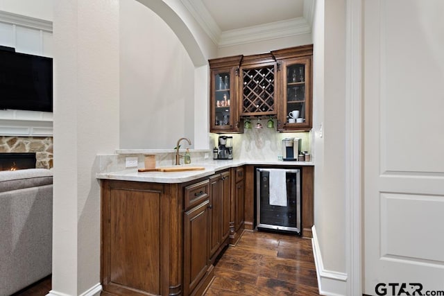 bar featuring ornamental molding, beverage cooler, dark hardwood / wood-style floors, and a fireplace