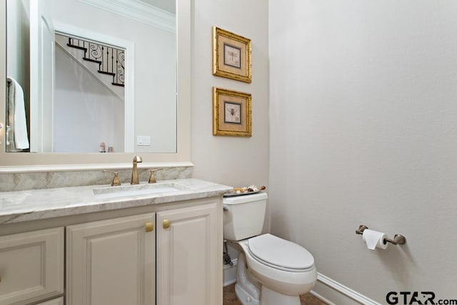 bathroom with toilet, vanity, and crown molding