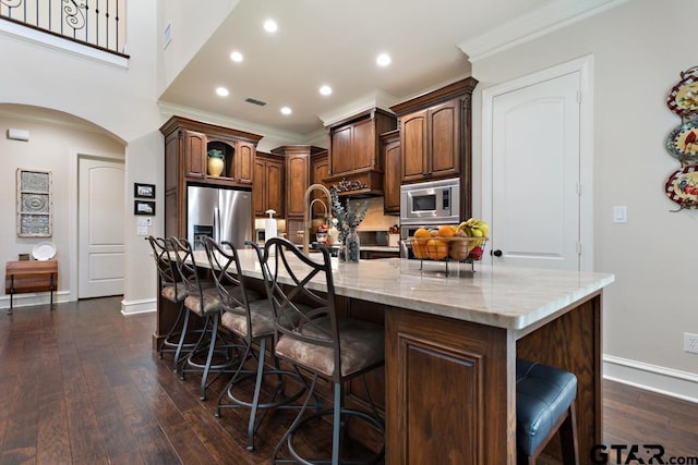 kitchen with dark wood-type flooring, a breakfast bar, a spacious island, and appliances with stainless steel finishes