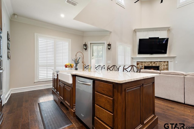 kitchen with a wealth of natural light, a center island with sink, and dark hardwood / wood-style floors