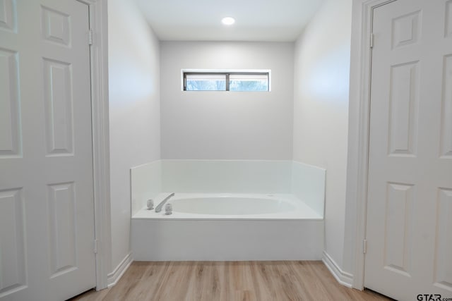 bathroom with wood finished floors and a bath