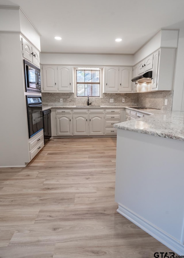 kitchen featuring decorative backsplash, a sink, under cabinet range hood, and black appliances