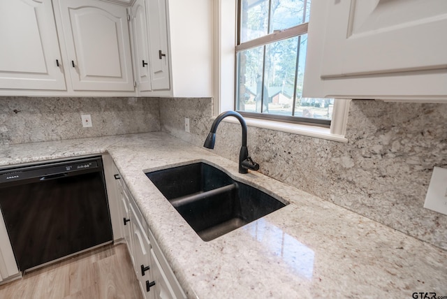 kitchen with white cabinets, dishwasher, a sink, and light stone countertops