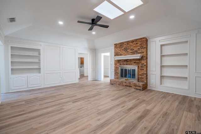 unfurnished living room featuring vaulted ceiling with skylight, a decorative wall, a fireplace, visible vents, and built in features