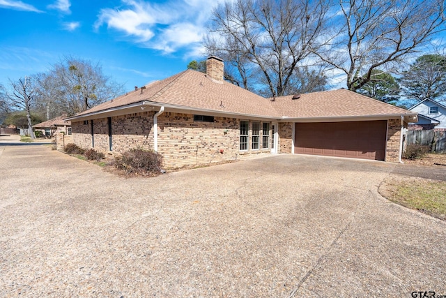 view of front facade with a garage, brick siding, driveway, roof with shingles, and a chimney