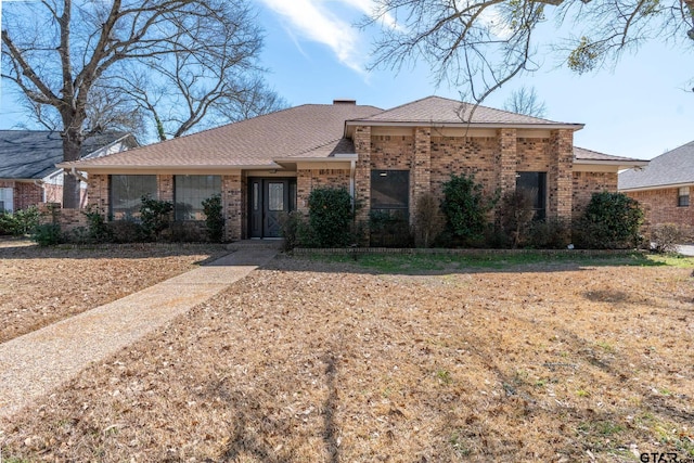 single story home featuring a shingled roof and brick siding