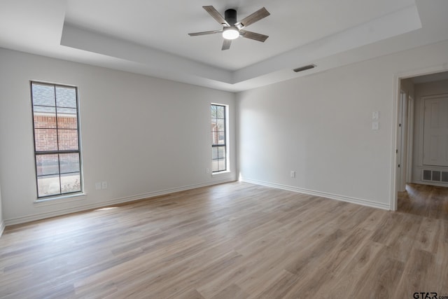 empty room featuring plenty of natural light, a raised ceiling, and visible vents