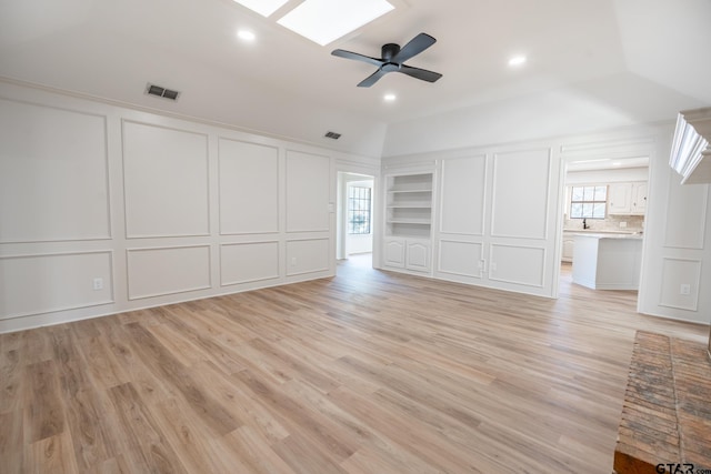 unfurnished bedroom with light wood-style floors, a skylight, visible vents, and a decorative wall