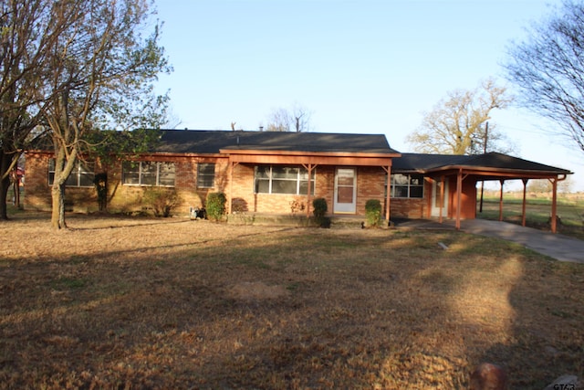 ranch-style home with an attached carport, concrete driveway, and a front yard