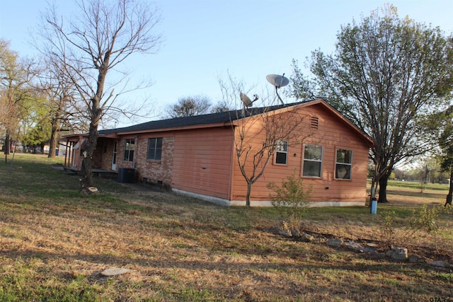 view of side of property with central AC unit and a lawn