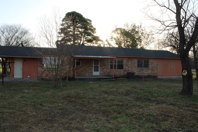 rear view of property featuring cooling unit, a lawn, and brick siding