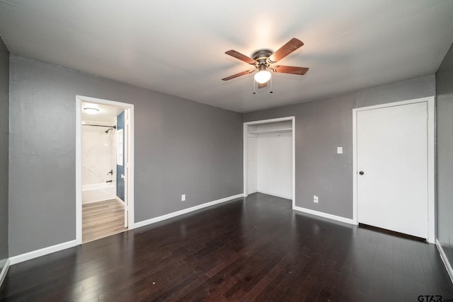 unfurnished bedroom featuring ceiling fan, ensuite bathroom, dark hardwood / wood-style floors, and a closet