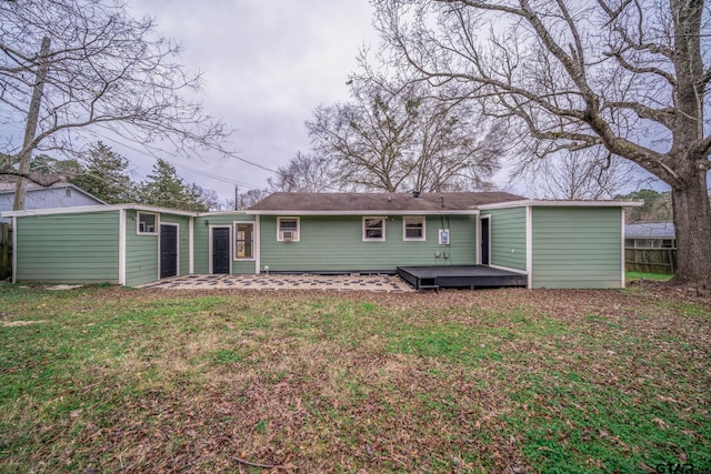 rear view of property featuring a wooden deck and a lawn