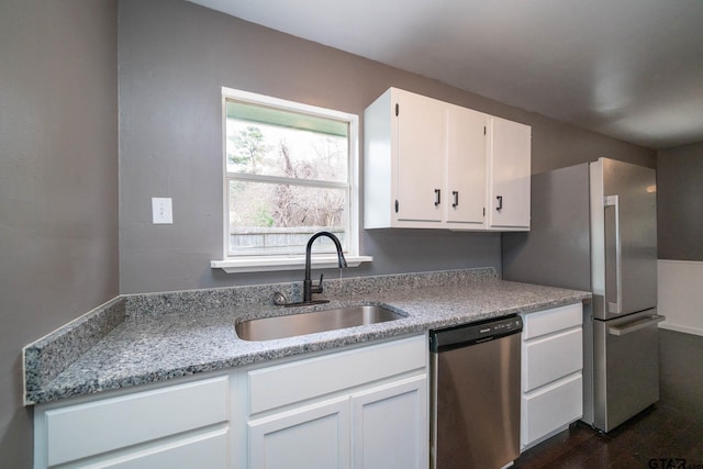 kitchen featuring light stone countertops, sink, white cabinets, and dishwasher