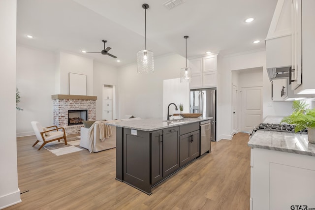 kitchen featuring sink, white cabinetry, light stone counters, hanging light fixtures, and appliances with stainless steel finishes