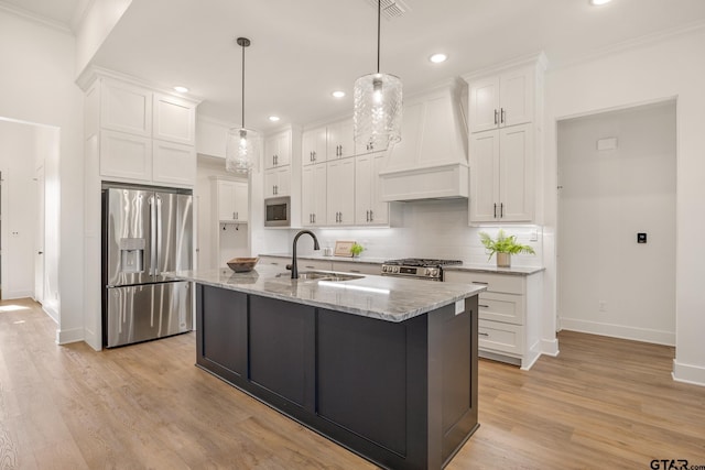 kitchen with wall chimney exhaust hood, sink, white cabinetry, hanging light fixtures, and stainless steel appliances