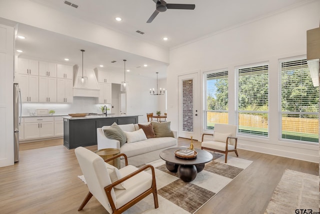 living room featuring ornamental molding, sink, ceiling fan with notable chandelier, and light hardwood / wood-style floors