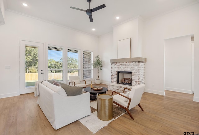 living room featuring ornamental molding, ceiling fan, a fireplace, and light hardwood / wood-style flooring