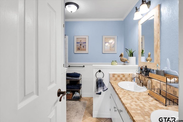 bathroom with tile patterned flooring, ornamental molding, and vanity