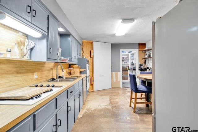 kitchen with white stovetop, sink, a textured ceiling, and gray cabinetry