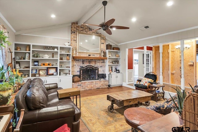 living room with vaulted ceiling with beams, wood-type flooring, a brick fireplace, ornamental molding, and ceiling fan