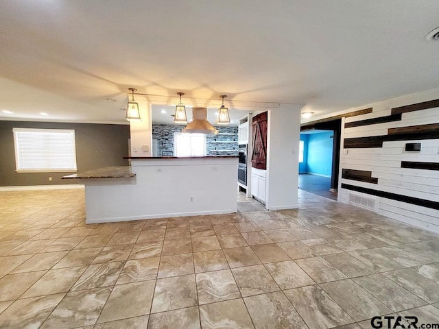 kitchen featuring decorative backsplash, decorative light fixtures, and wall chimney exhaust hood