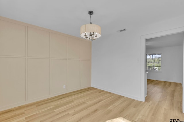 empty room featuring light hardwood / wood-style flooring and a chandelier