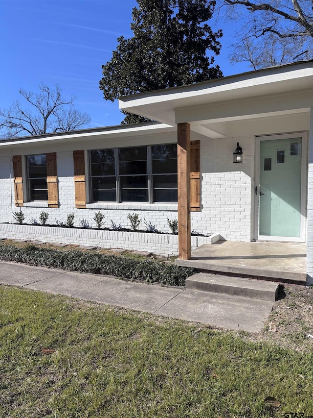 entrance to property featuring covered porch and brick siding