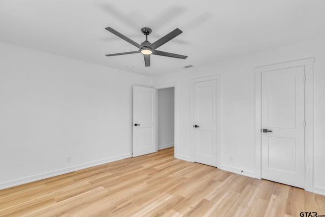 unfurnished bedroom with ceiling fan, light hardwood / wood-style floors, and two closets