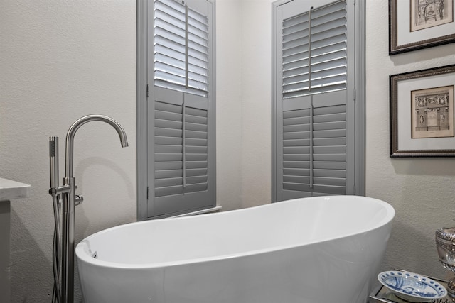 full bathroom with a textured wall and a soaking tub