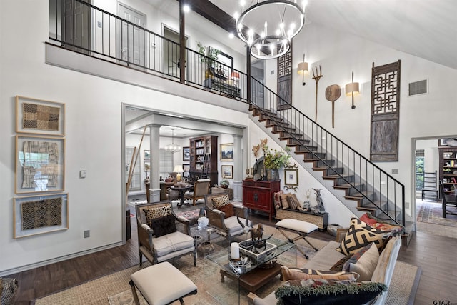 living room featuring a chandelier, hardwood / wood-style floors, a towering ceiling, visible vents, and stairway