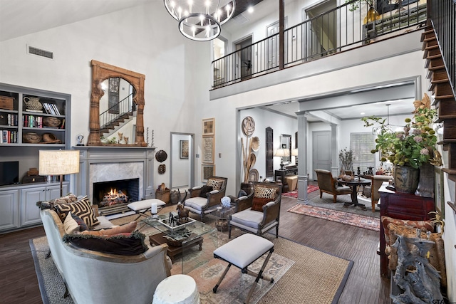 living area featuring visible vents, dark wood-style flooring, a high ceiling, and a notable chandelier