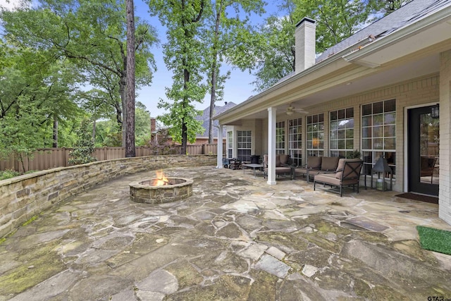 view of patio with ceiling fan, a fire pit, and a fenced backyard