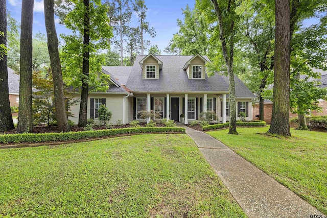 new england style home featuring brick siding, a shingled roof, and a front lawn