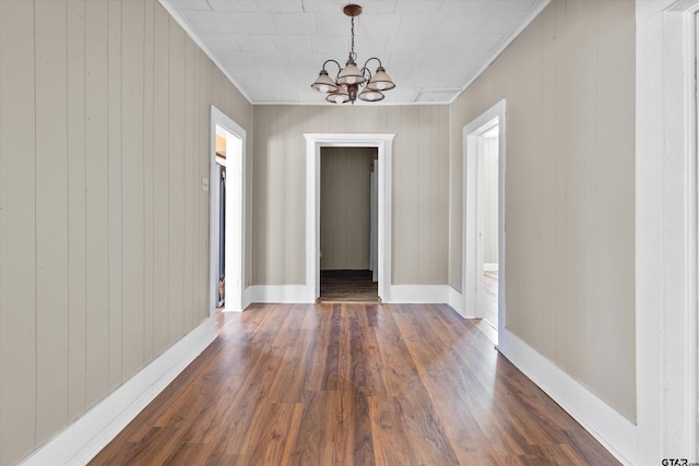 interior space featuring wood walls, dark hardwood / wood-style floors, crown molding, and a notable chandelier