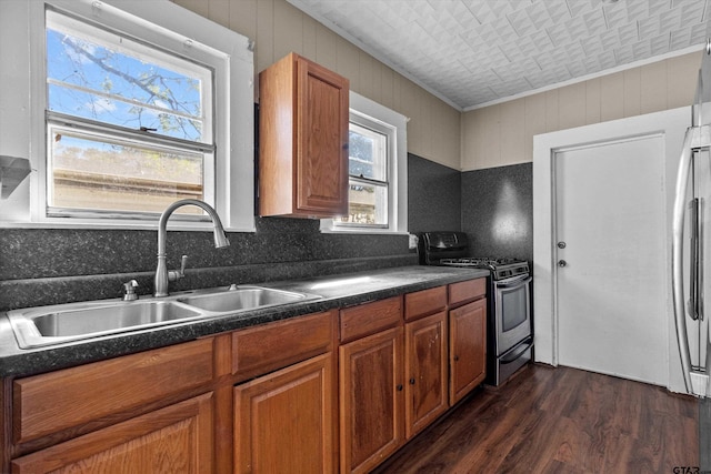 kitchen featuring stainless steel gas range oven, plenty of natural light, sink, and dark hardwood / wood-style flooring