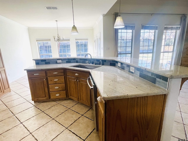 kitchen featuring visible vents, brown cabinetry, decorative light fixtures, crown molding, and a sink