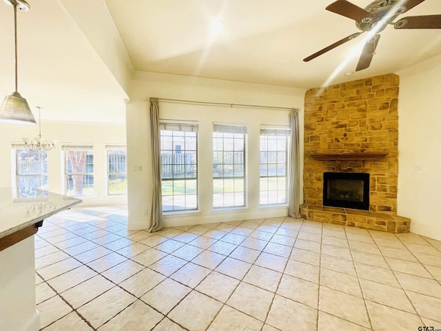 unfurnished living room featuring light tile patterned floors, ornamental molding, ceiling fan with notable chandelier, and a fireplace