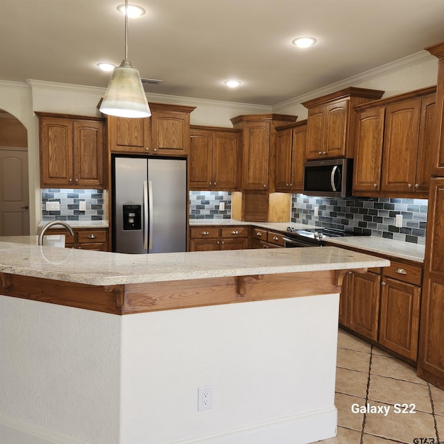 kitchen with arched walkways, appliances with stainless steel finishes, light tile patterned flooring, and brown cabinets