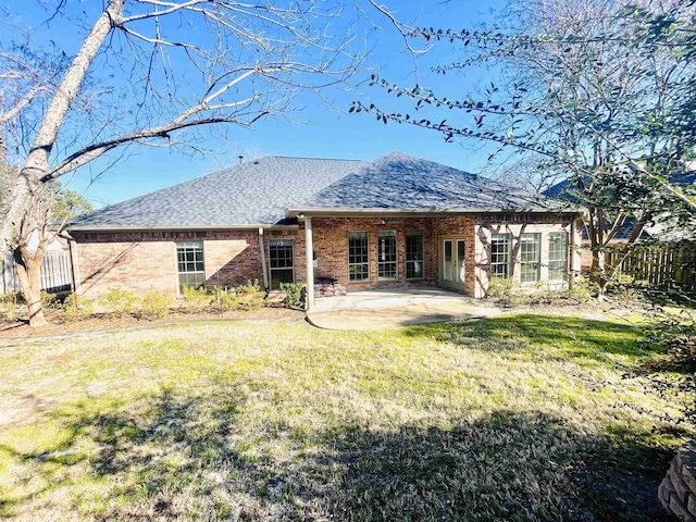 back of property with a patio, brick siding, a lawn, and fence