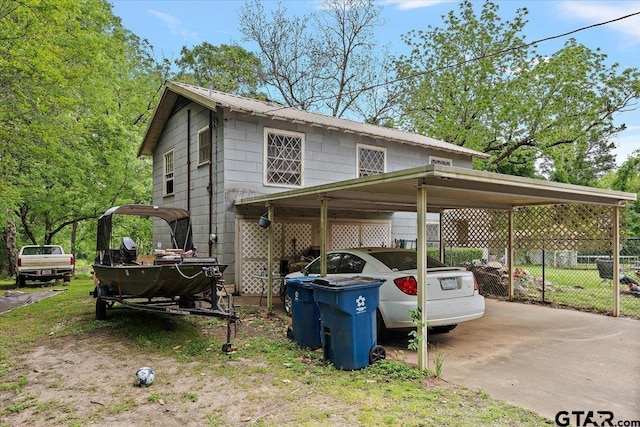 view of side of property with a carport, driveway, and fence
