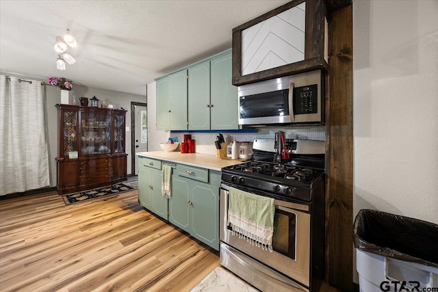 kitchen featuring green cabinets, appliances with stainless steel finishes, light countertops, and light wood-style floors